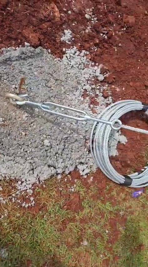 Ancoragem no solo: olhal, elo/esticador tipo corrente e rolo de cabo de aço galvanizado sobre concreto recente (quadra coberta).